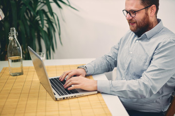 Young male architect sitting at his desk and typing.	