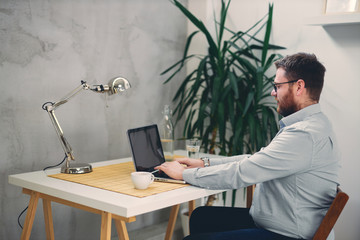 Young male architect sitting at his desk and typing.	