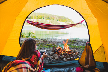 woman laying in yellow tent looking at bonfire © phpetrunina14