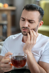 Dark-haired young man suffering from the toothache