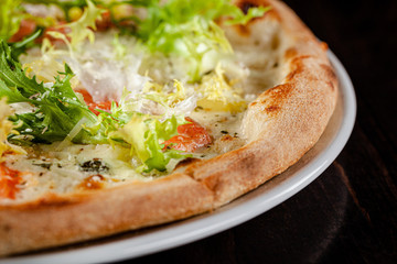 Italian cuisine. Thin pizza with large sides. Pizza with salmon, cheese sauce, lettuce. background image, copy space text