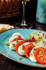 Italian cuisine. Antipasti appetizer. Caprese made of mozzarella and tomato cheese and pesto. Serving dishes in a restaurant in a boulevard plate. background image, copy space text