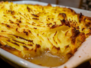 Close up and selective focus of a freshly baked cottage pie with a crispy mashed potato topping out of the oven