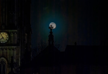 Fototapeta na wymiar A full moon and the silhouette of Leeds Minster in Yorkshire, UK