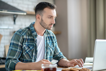 Young man in a checkered shirt working on a laptop