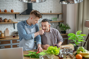 Young man in an apron feeding his partner