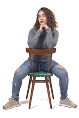 portrait of a woman sitting on a chair in white background, rear view of the chair and looking at...