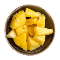 Chopped ripe pineapple in ceramic bowl isolated on white background. Top view.