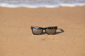 Mirrored safety glasses lie on the sand of a beach against the background  ocean.
