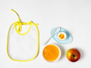 Bib, baby puree, spoon, Apple. The view from the top, flat lay.The concept of healthy nutrition for children.