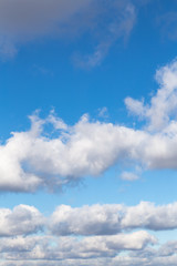 Fototapeta premium Snow-white fluffy clouds against the blue sky. Vertical.