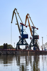 Cranes in cargo port translating coal. Industrial scene. Big port-cranes. Danube river