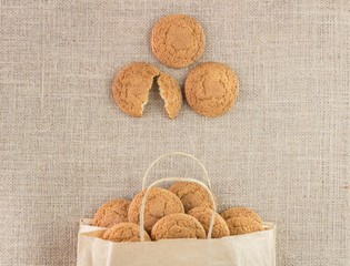 oatmeal cookies in a paper bag on burlap. Concept photo - vegetable food, eco-friendly packaging and natural background