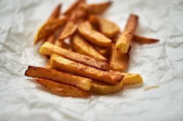 Tasty homemade potato french fries on white paper background