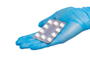 Surgeon's hand in a blue medical glove holds a blister of tablets isolated on a white background