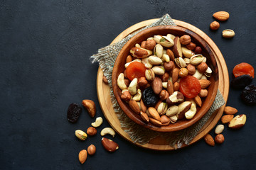 Wooden bowl with assortment of dried fruits and nuts. Top view with copy space.