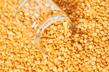 Dried grain of peas poured out of glass jar. Copy space