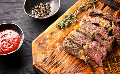 Juicy medium rare beef steak on board with herbs spices and salt.