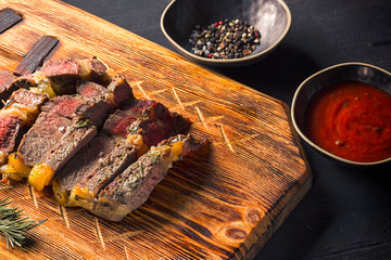 Juicy medium rare beef steak on board with herbs spices and salt.