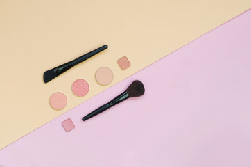 Colorful cosmetics lying on pink and yellow background. Makeup set. Flatlay background for design with copyspace