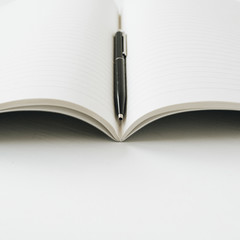 Open notebook with pen on white background.