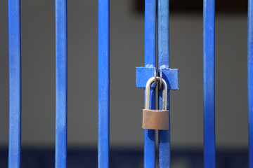 Master key or Padlock locked in front of a fence gate.