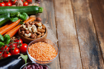 Concept of healthy vegan food, clean eating. Fresh raw ingredients,  wooden background: vegetables, nuts, beans, lentils. Ripe seasonal product for clean meal. Copy space for text