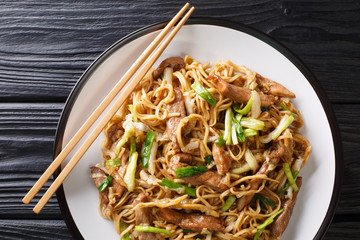 Stir-fried Shanghai noodles with napa cabbage green onions and pork closeup in a plate. Horizontal top view