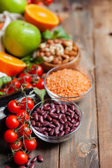 Concept of healthy vegan food, clean eating. Fresh raw ingredients on wooden background: vegetables, fruits, nuts, beans and lentils. No plastic, eco-friendly shopping for zero waste. Copy space