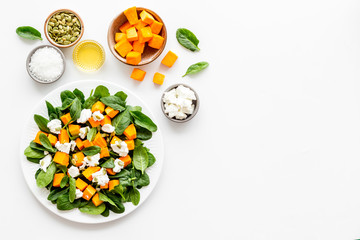 Salad with pumpkin and basil - near ingredients - on white background top-down copy space