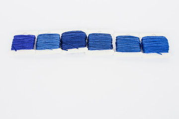 Classic blue thread for embroidery isolated on white background. Materials for needlework. Female hobby. View from above. Copy space.