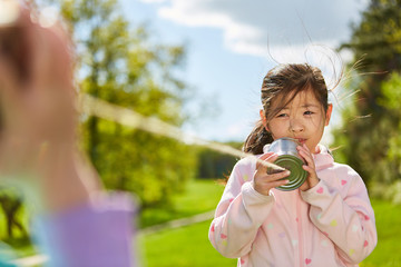 Mädchen spielt mit Dosentelefon mit Schnur