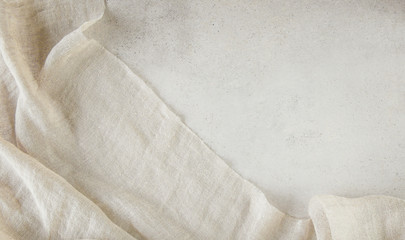 Pure washed linen cloth on light grunge stone background. Natural washed linen fabric on stone tile surface with copy space..
