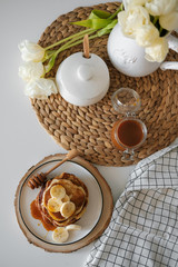 delicious American pancakes with bananas and honey on the plate for a breakfast. selective focus. Scandinavian style kitchen. 