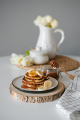 delicious American pancakes with bananas and honey on the plate for a breakfast. selective focus. Scandinavian style kitchen. 