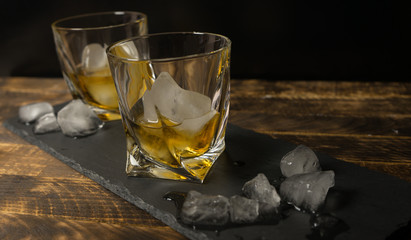 glass of scotch whiskey and ice on wooden table