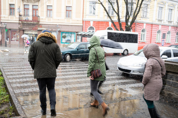 Fototapeta na wymiar Busy city street people on zebra crossing in a rainy day. Dangerous situation. Defocused image