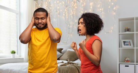 relationships and people concept - unhappy african american couple having argument over home...