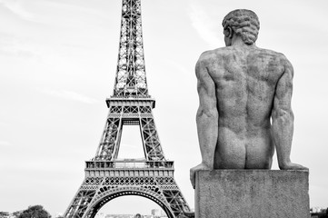 Fototapeta na wymiar Black and white view of Eiffel Tower with statue of masculine figure in the foreground