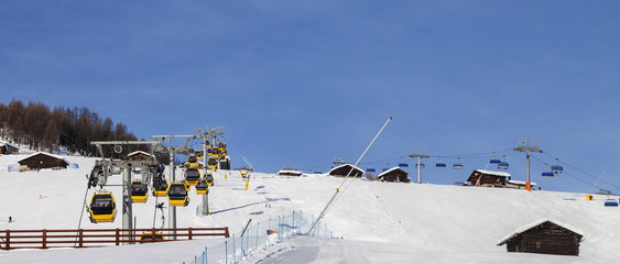 Snowy ski track prepared with snow grooming machine, gondola lift, chair-lift