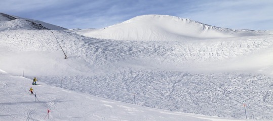 Trace for ski slalom with gates marked by flags, prepared by snowcat and off-piste slope