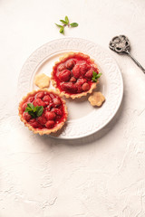 a dessert, strawberry tartlets on a white plate, on a light backdrop