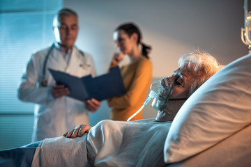 Senior patient at the hospital and doctor talking with a family member - obrazy, fototapety, plakaty