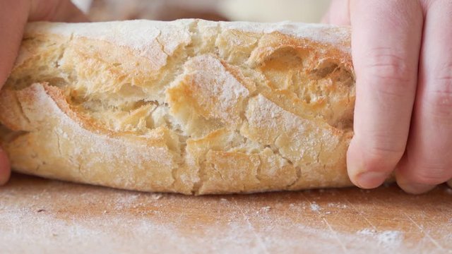 Slow motion of hands breaking a freshly baked loaf of bread