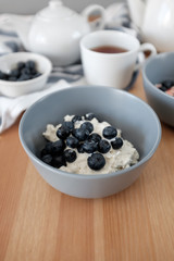Tasty breakfast of Tvorog, farmers cheese, curd cheese or cottage cheese and blueberries in gray bowls. 