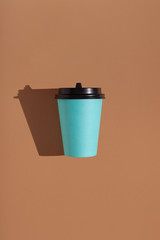 Brown background with one paper blue cup. Trend hard shadow. Place for your text.