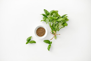 greens, culinary and flavoring concept - bunch of fresh basil herb and dry seasoning in cup on...