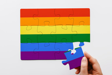 LGBT concept. Hand putting the last piece of a rainbow colored puzzle. Gay Pride. Top view 