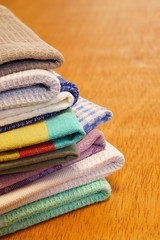 Obraz na płótnie Canvas Pile of linen and cotton kitchen towels on a wooden table background. Stack of colorful dish towels with copy space. 