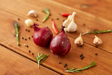 food, culinary and healthy eating concept - red onion, garlic, chili pepper and rosemary on wooden table